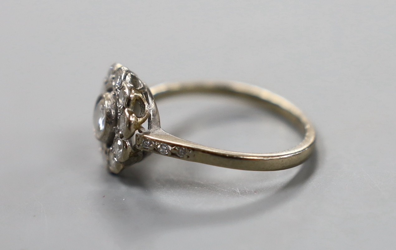 An 18ct white metal and eleven stone diamond set circular cluster ring, size N, gross weight 3.4 grams.